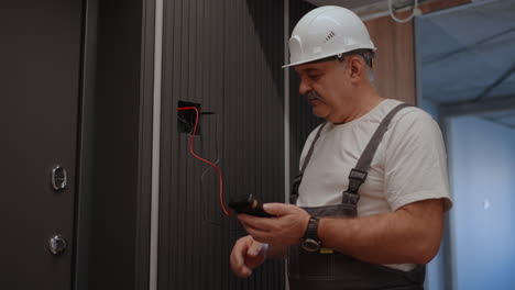 Portrait-Electrician-checks-the-operation-of-the-wall-control-unit-of-lamps-with-the-system-of-modern-house-after-installation-and-repair